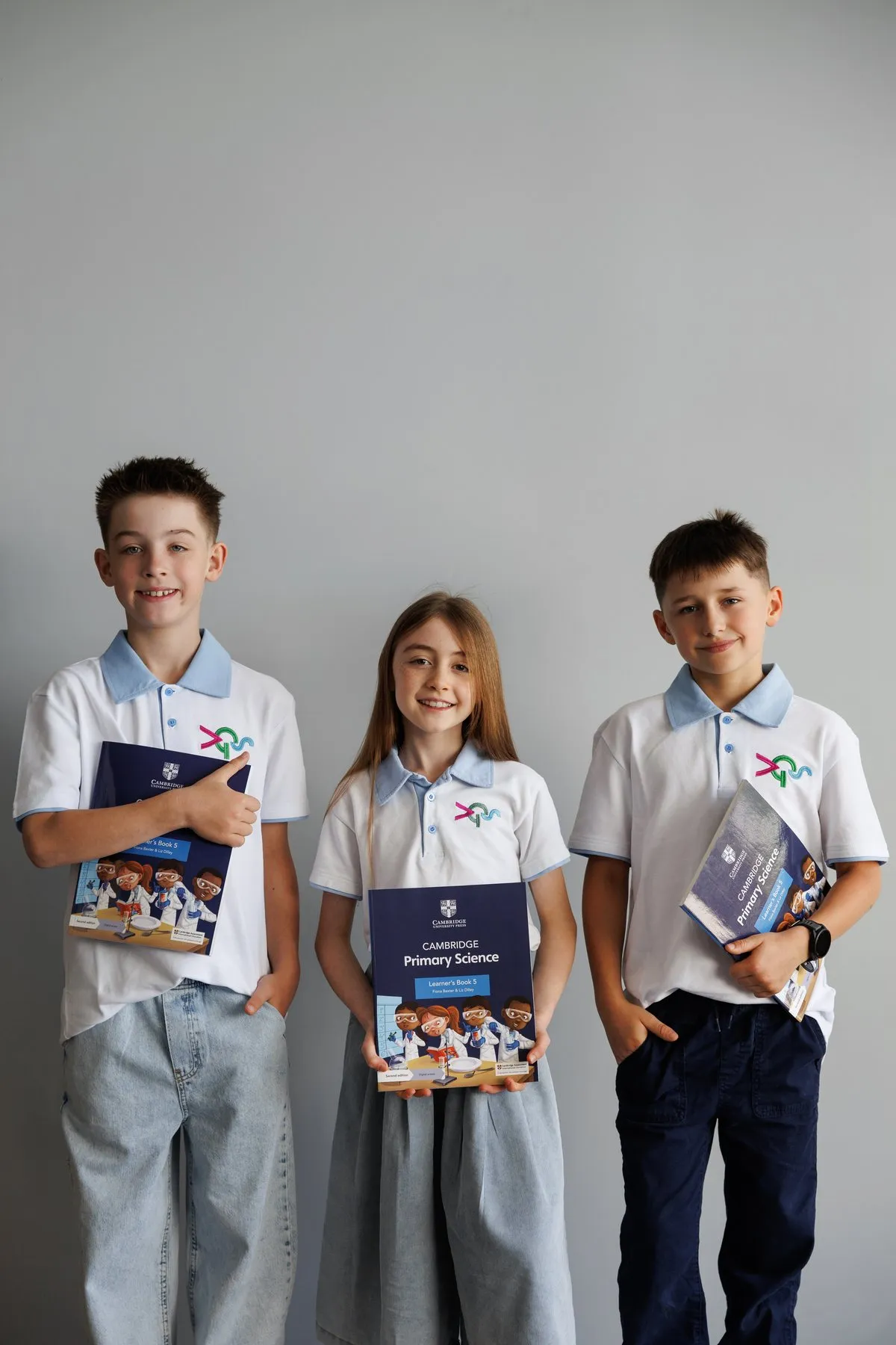 Троє учнів у формі Advance Green School з підручниками